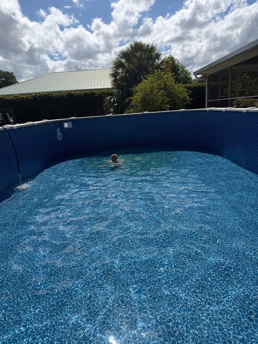 Boy swimming in the clear water of a newly filled above-ground pool the day the install finished
