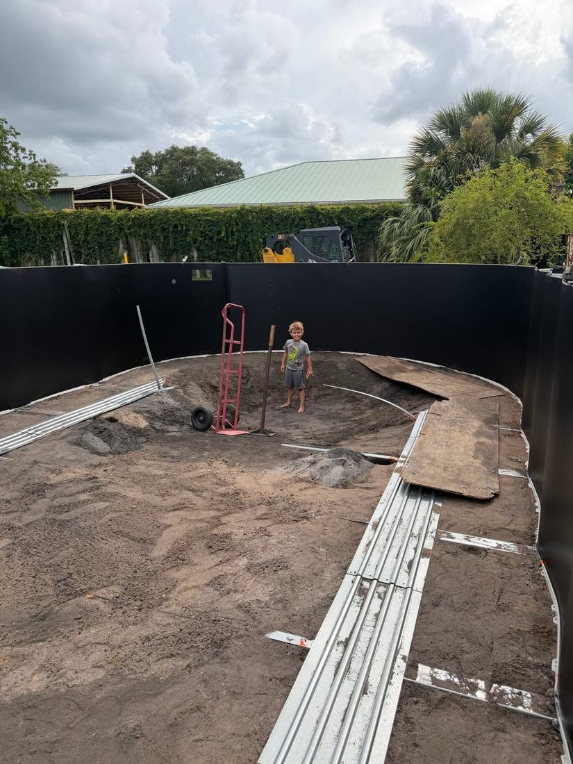 Oval above-ground pool wall standing on a finished sand base, ready for the liner
